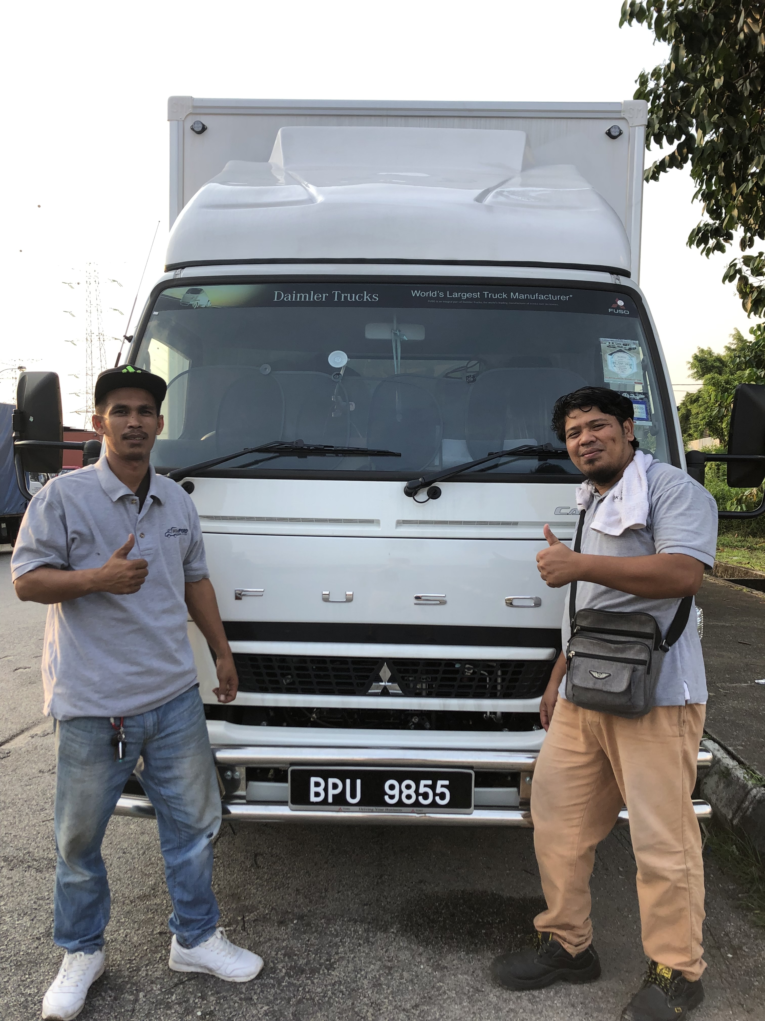Two professional Mileford team members giving thumbs up in front of a lorry, ensuring reliable service.